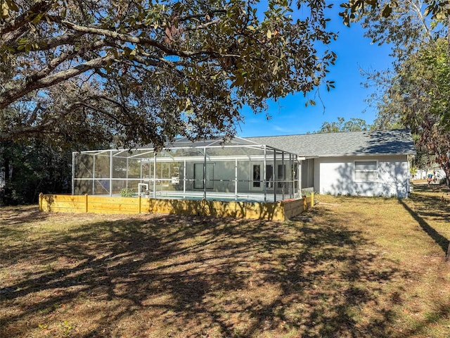 rear view of house with a lawn, a lanai, and an outdoor pool