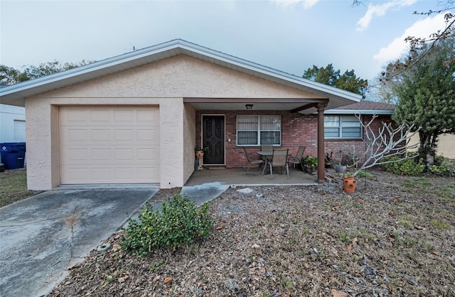 ranch-style house featuring concrete driveway, a garage, and stucco siding