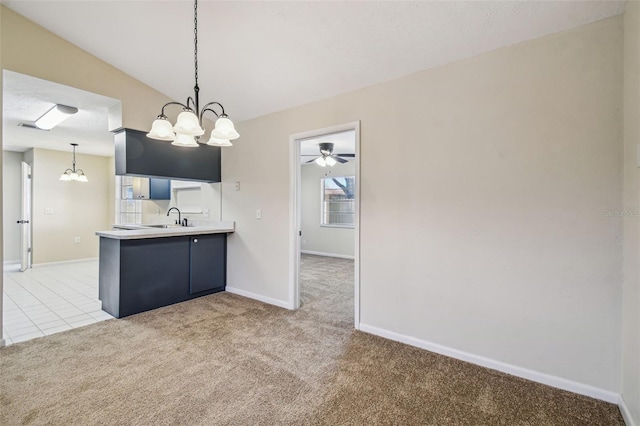 kitchen featuring sink, hanging light fixtures, light carpet, ceiling fan with notable chandelier, and kitchen peninsula