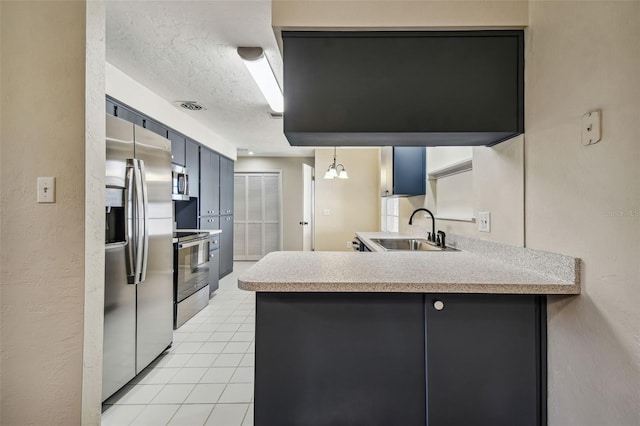 kitchen with light tile patterned flooring, appliances with stainless steel finishes, sink, kitchen peninsula, and a textured ceiling