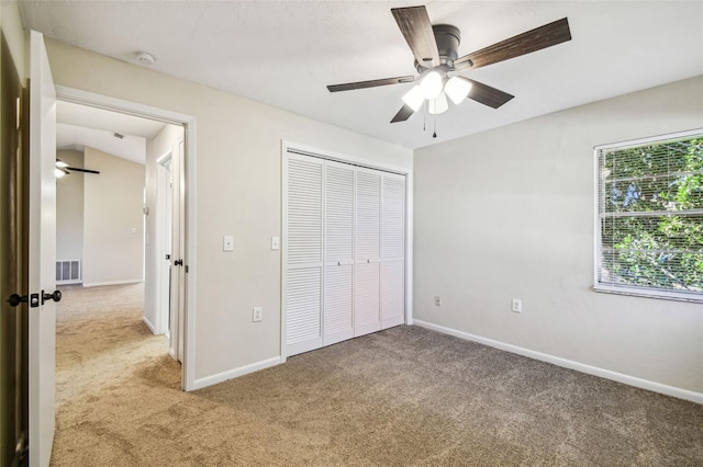 unfurnished bedroom featuring ceiling fan, a closet, and light carpet