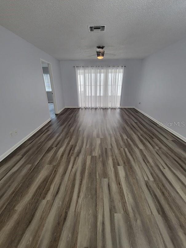 unfurnished room with a textured ceiling and dark hardwood / wood-style flooring