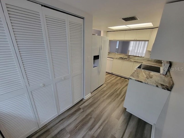 kitchen with white cabinetry, sink, white fridge with ice dispenser, range, and light wood-type flooring