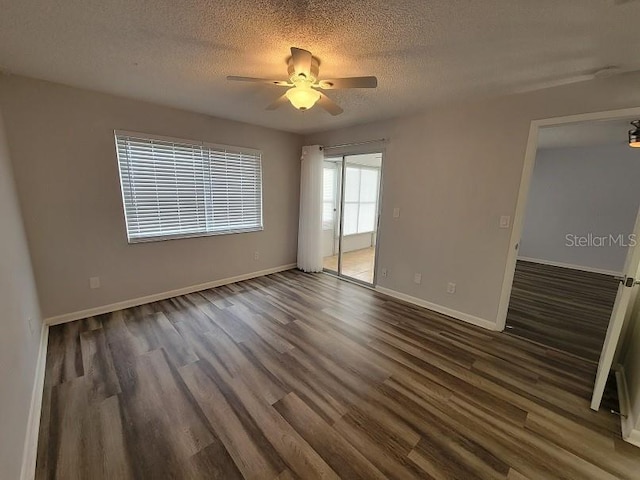 empty room with ceiling fan, dark wood-type flooring, and a textured ceiling