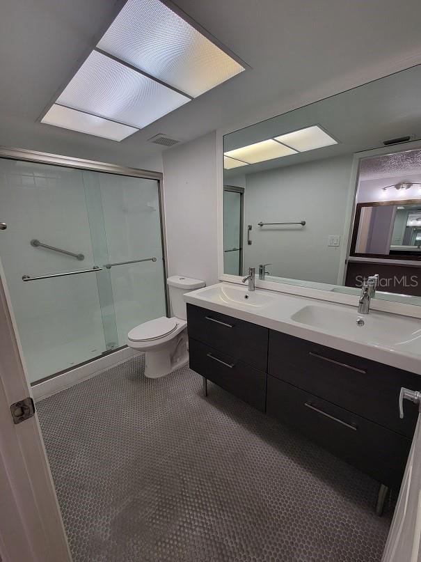 bathroom with walk in shower, tile patterned floors, vanity, and toilet