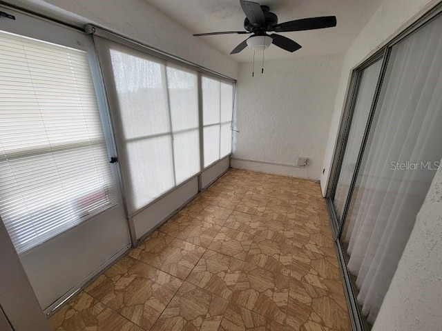 unfurnished sunroom with ceiling fan