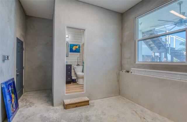 bathroom with toilet, ceiling fan, and concrete floors