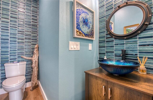 bathroom with tile walls, toilet, vanity, and hardwood / wood-style floors