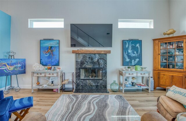 living room with a high end fireplace and light hardwood / wood-style flooring