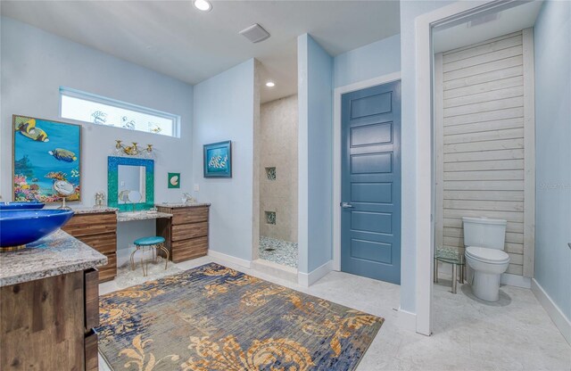 bathroom with toilet, a tile shower, tile patterned floors, and vanity