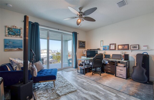 office space featuring light hardwood / wood-style flooring, ceiling fan, and a textured ceiling