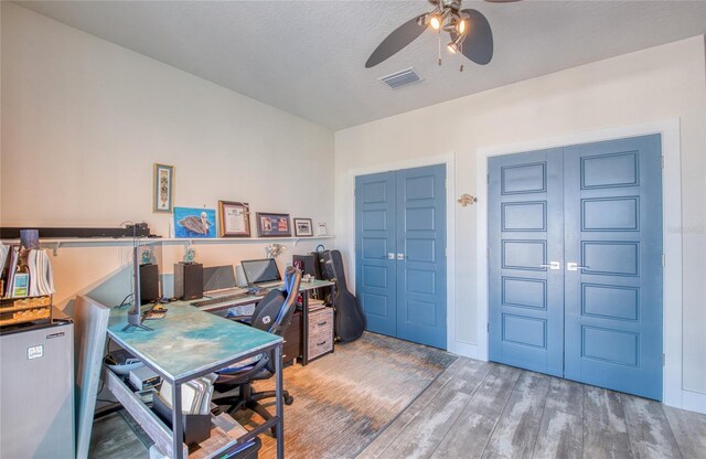 home office with hardwood / wood-style floors, ceiling fan, and a textured ceiling