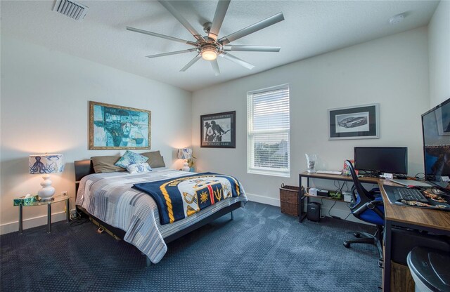 bedroom featuring dark carpet, ceiling fan, and a textured ceiling