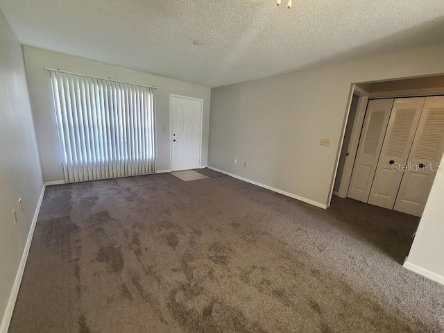 interior space with a textured ceiling and dark colored carpet