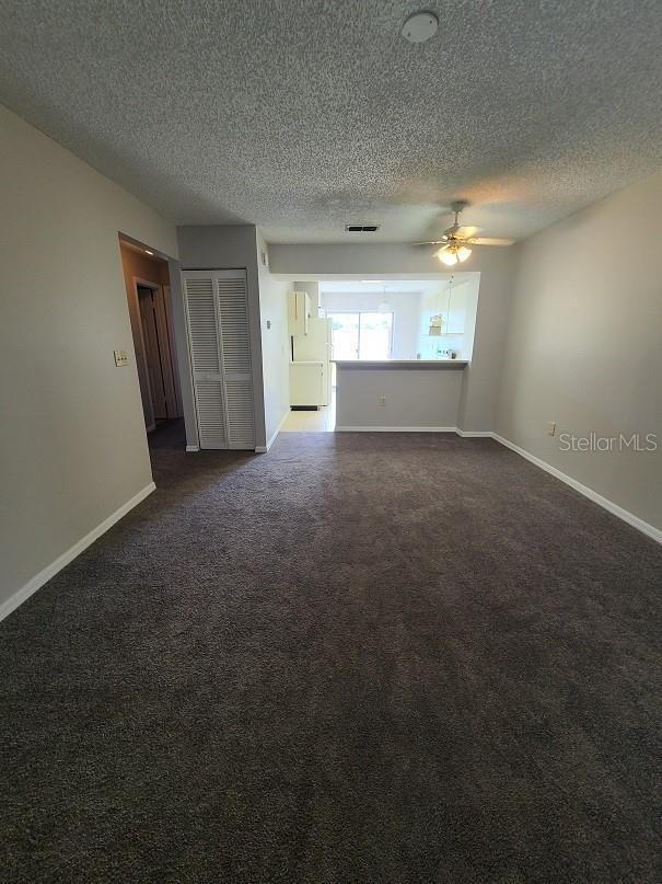 carpeted spare room featuring ceiling fan and a textured ceiling