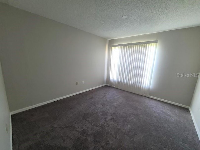 unfurnished room with dark colored carpet and a textured ceiling