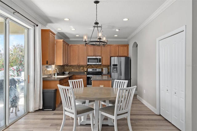 kitchen with crown molding, appliances with stainless steel finishes, hanging light fixtures, a kitchen island, and decorative backsplash