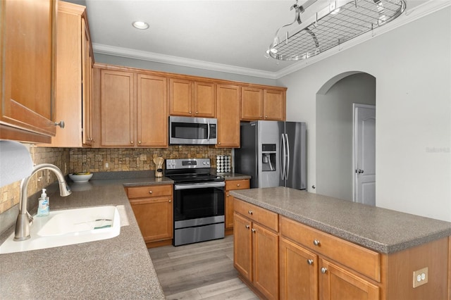 kitchen featuring tasteful backsplash, sink, stainless steel appliances, crown molding, and light hardwood / wood-style flooring