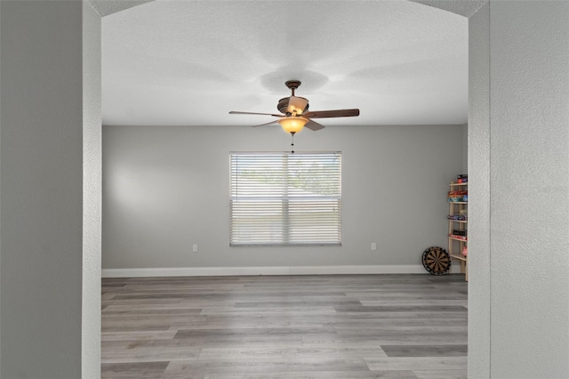 empty room with ceiling fan, light hardwood / wood-style floors, and a textured ceiling