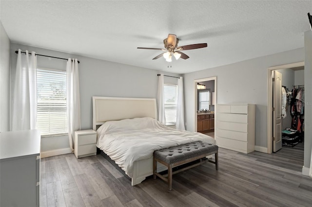 bedroom with ensuite bath, a textured ceiling, dark hardwood / wood-style flooring, a closet, and ceiling fan