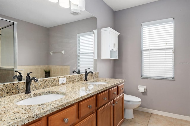 bathroom featuring vanity, a healthy amount of sunlight, tile patterned floors, and toilet