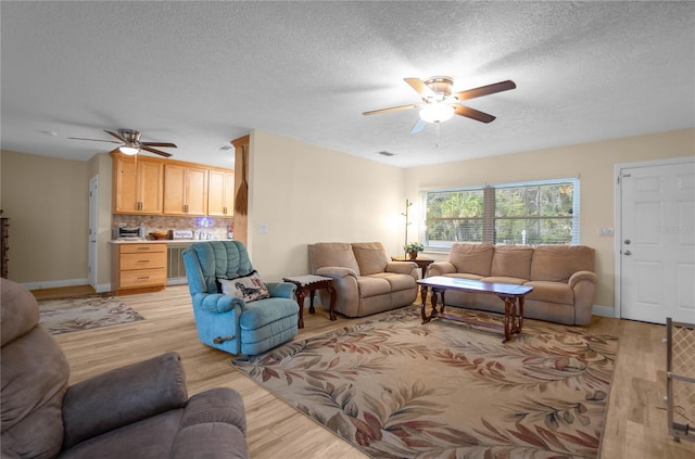 living room featuring ceiling fan, a textured ceiling, and light wood-type flooring