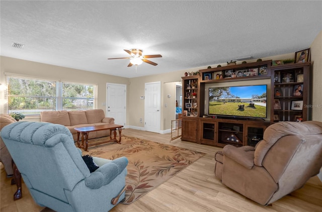 living room featuring ceiling fan, a textured ceiling, and light wood-type flooring