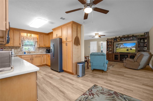 kitchen featuring stainless steel refrigerator with ice dispenser, light brown cabinetry, sink, light wood-type flooring, and decorative backsplash