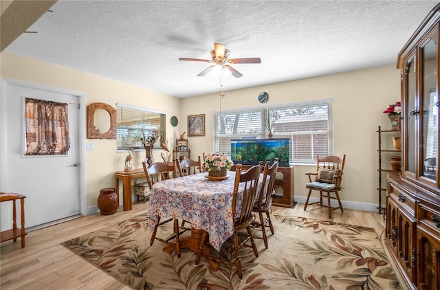 dining area with ceiling fan, light hardwood / wood-style floors, and a textured ceiling