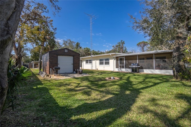 rear view of property featuring a fire pit, a sunroom, a yard, and a storage shed