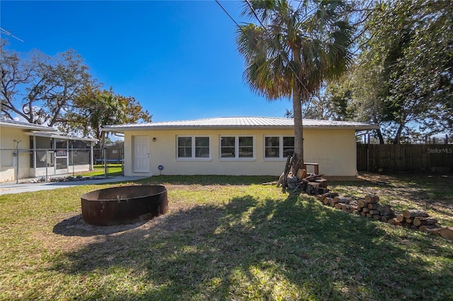 back of house featuring a fire pit and a lawn