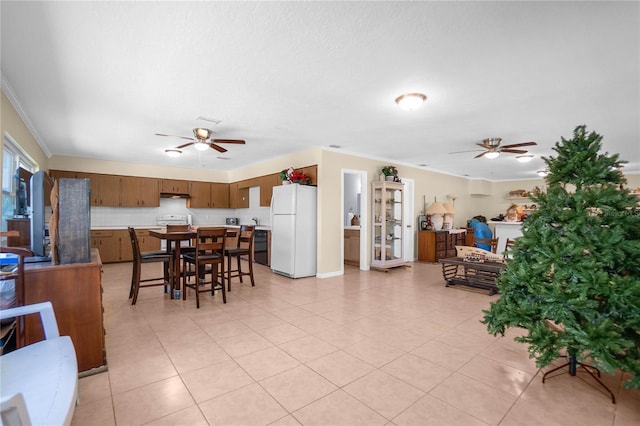 tiled dining space featuring crown molding, a textured ceiling, and ceiling fan