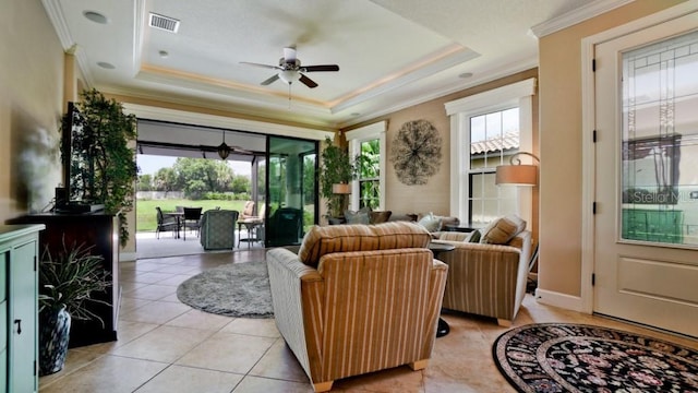 living room featuring ornamental molding, a healthy amount of sunlight, and a raised ceiling