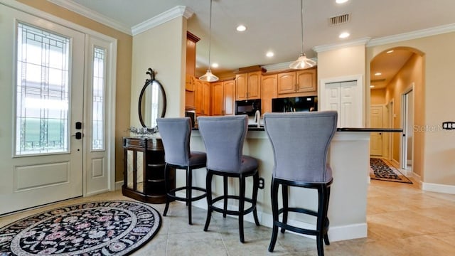 kitchen featuring crown molding, decorative light fixtures, a breakfast bar area, and black appliances