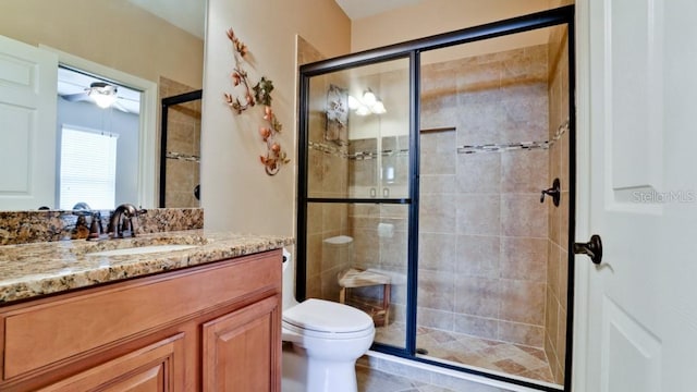 bathroom with vanity, an enclosed shower, toilet, and ceiling fan