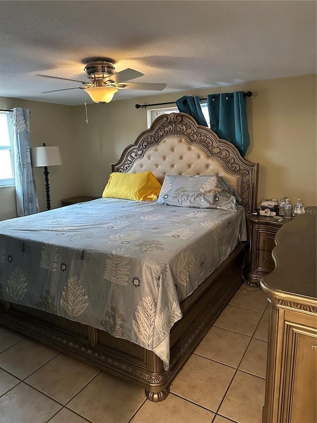 bedroom with ceiling fan, a textured ceiling, and light tile patterned flooring