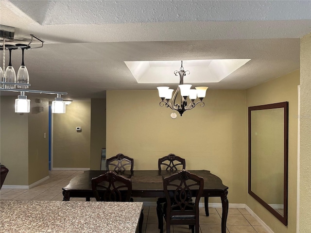 tiled dining area featuring a raised ceiling, an inviting chandelier, and a textured ceiling