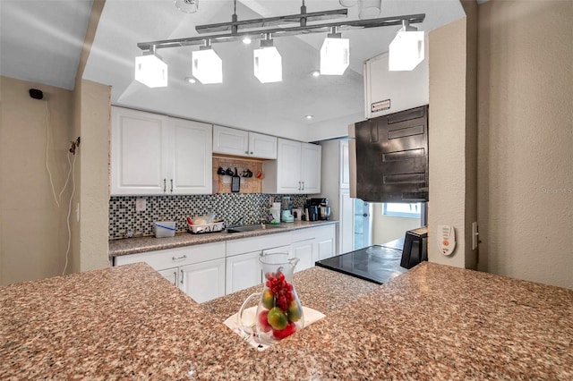 kitchen featuring tasteful backsplash, a sink, white cabinetry, and decorative light fixtures