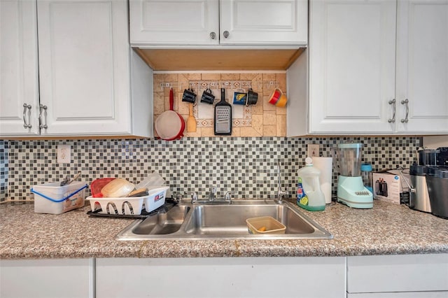 kitchen with white cabinets, light countertops, a sink, and backsplash