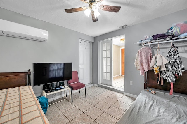 bedroom with a wall unit AC, visible vents, a ceiling fan, a textured ceiling, and baseboards