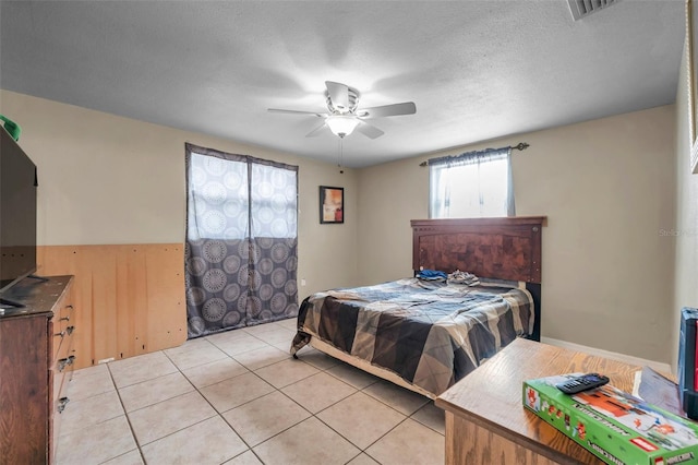 bedroom with light tile patterned floors, visible vents, a textured ceiling, and a ceiling fan