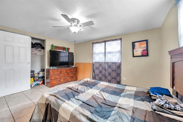 bedroom featuring ceiling fan, a closet, light tile patterned flooring, and a wainscoted wall