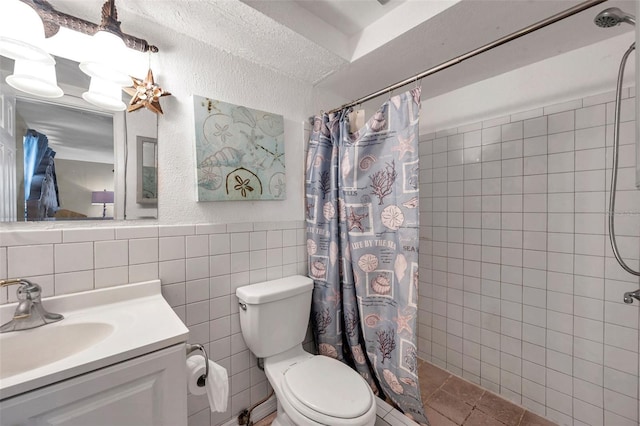 bathroom with tile walls, toilet, a tile shower, vanity, and tile patterned flooring