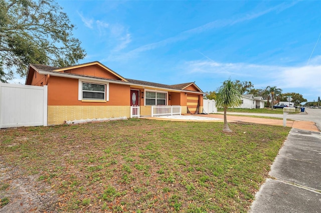 ranch-style home with brick siding, a porch, concrete driveway, a front yard, and fence