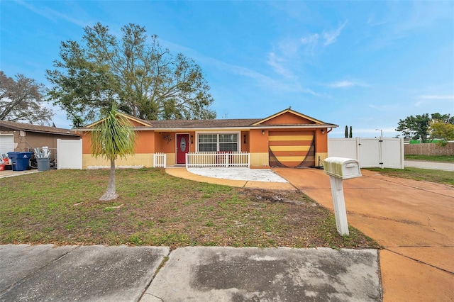 single story home featuring a garage, concrete driveway, a gate, stucco siding, and a front lawn