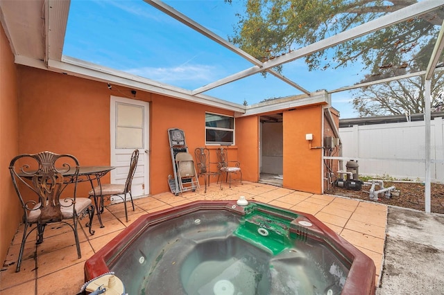 exterior space featuring glass enclosure, an outdoor hot tub, and fence