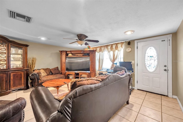 living area with visible vents, light tile patterned flooring, ceiling fan, a textured ceiling, and baseboards