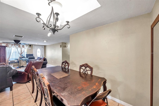 dining space with light tile patterned floors, baseboards, visible vents, and a chandelier