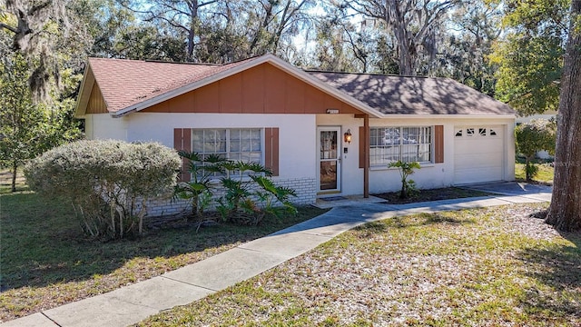 ranch-style home with a garage, roof with shingles, and a front yard