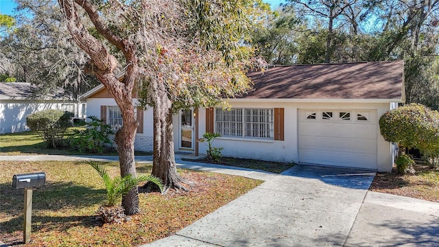 single story home with a garage, concrete driveway, a shingled roof, and stucco siding